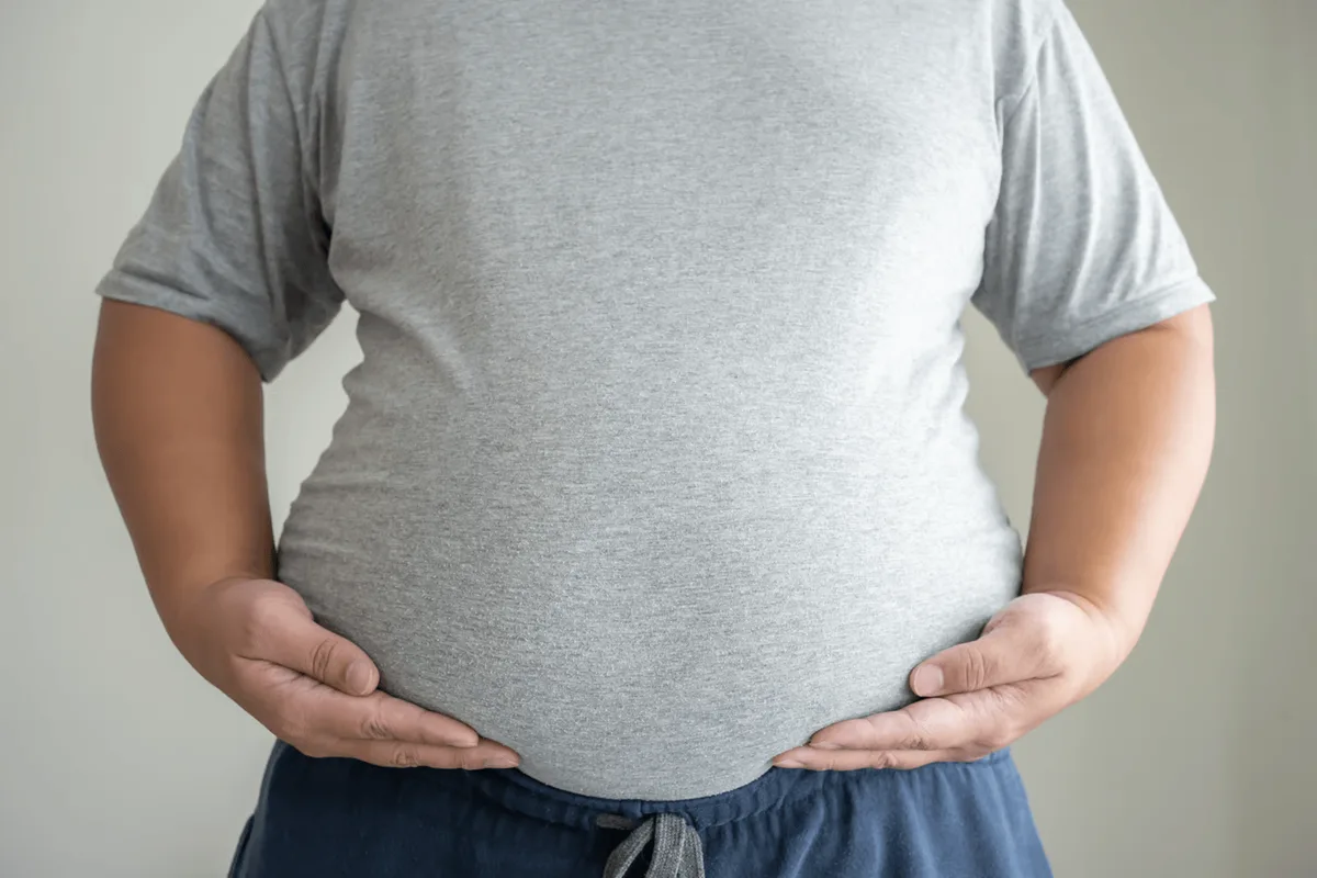 Person in a grey t-shirt with their hands resting on their stomach